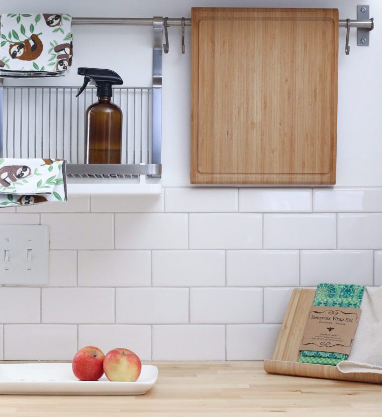 A bright, clean kitchen with subway tile, a spray bottle, cutting boards and apples