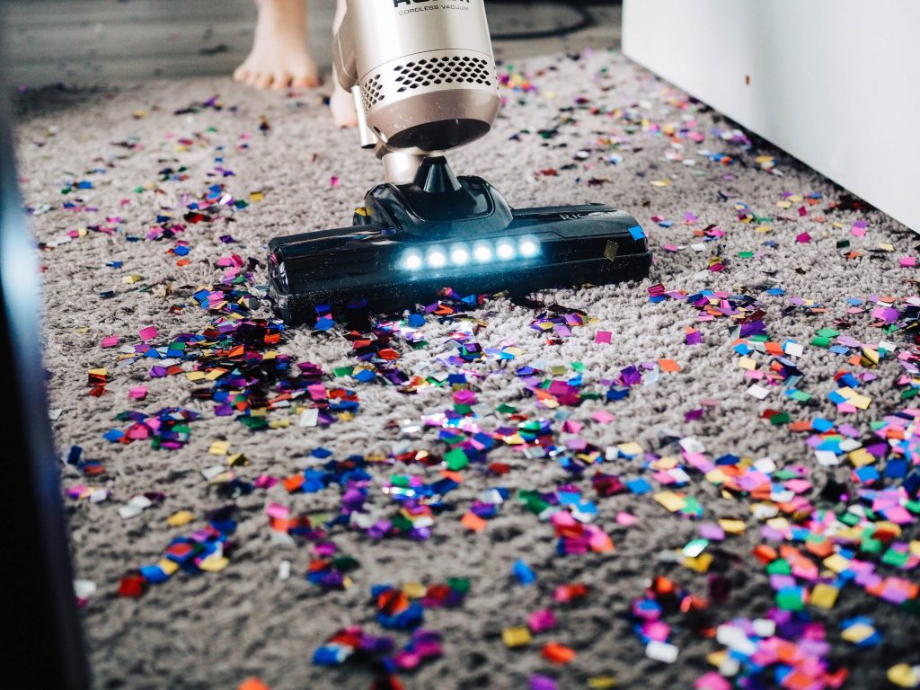A vacuum cleaning colourful confetti from a carpet