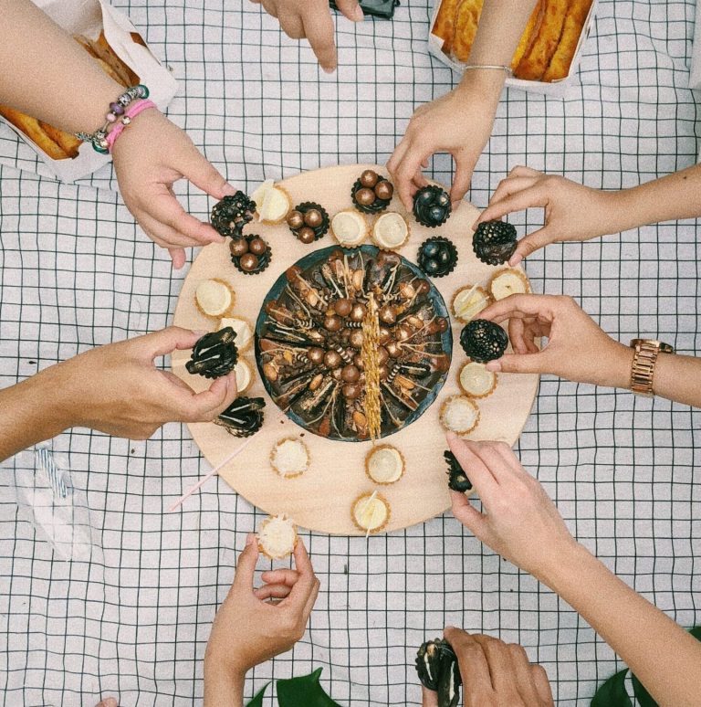 Overhead view of hands reaching for a shared snack board on a table
