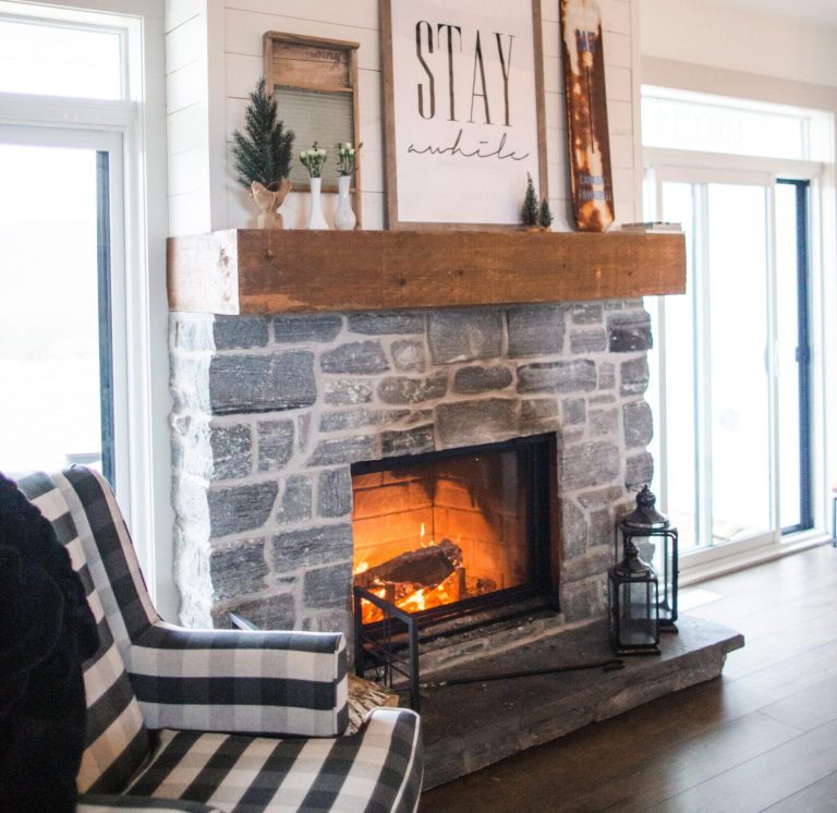 A cozy living room with a lit stone fireplace and a stay awhile sign