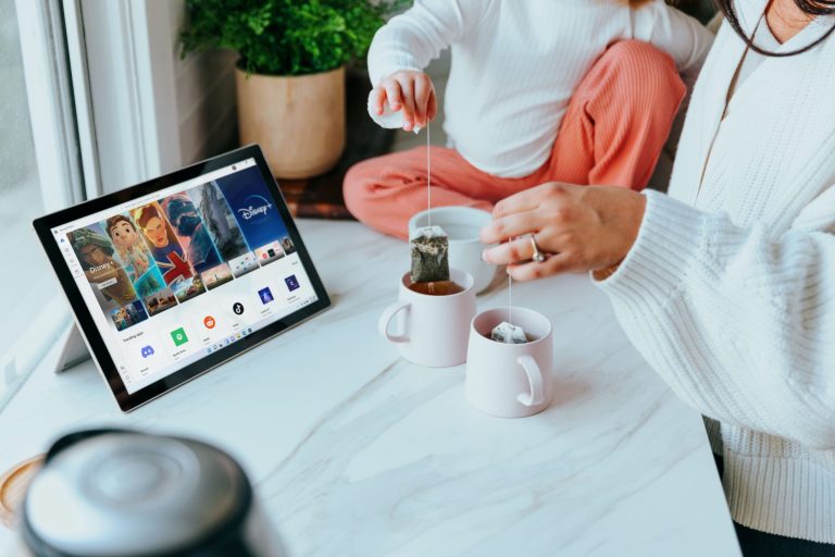 A person with coffee and a tablet relaxing at a table at home