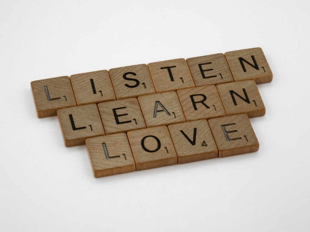 Scrabble tiles spelling the words listen, learn and love