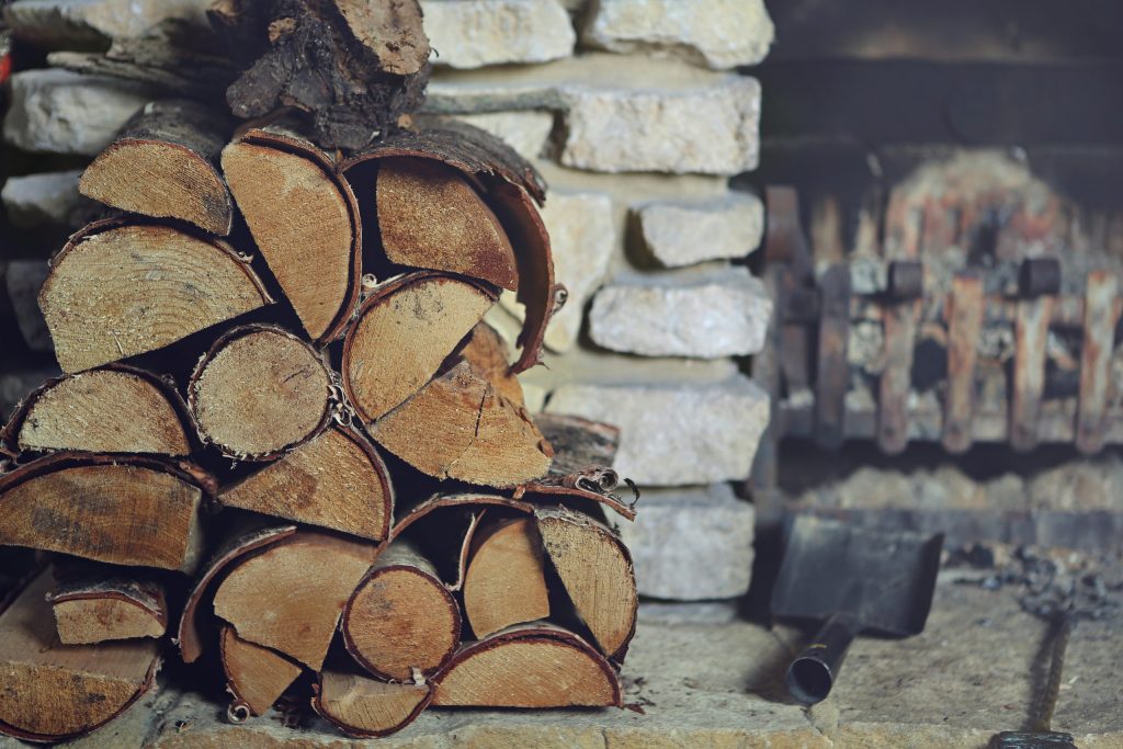 Neatly stacked firewood beside a stone fireplace