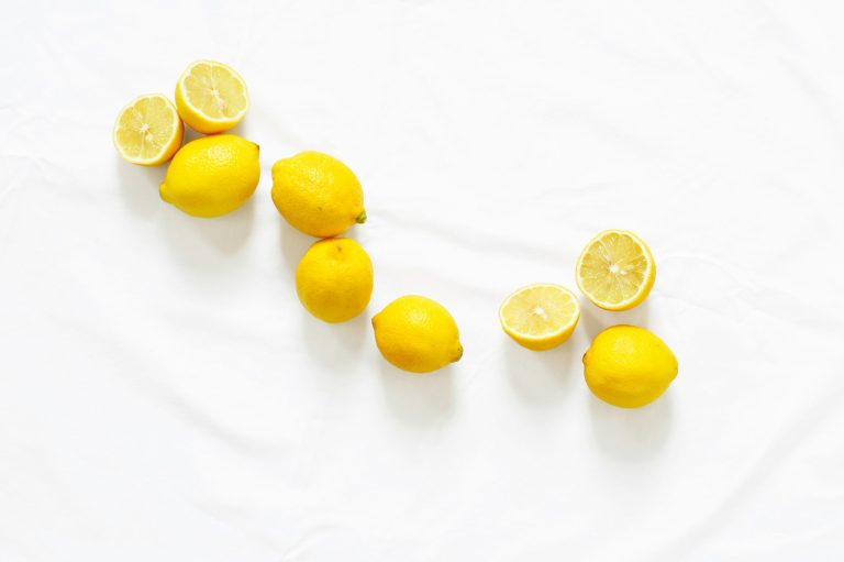 Fresh whole and halved lemons arranged on a white cloth