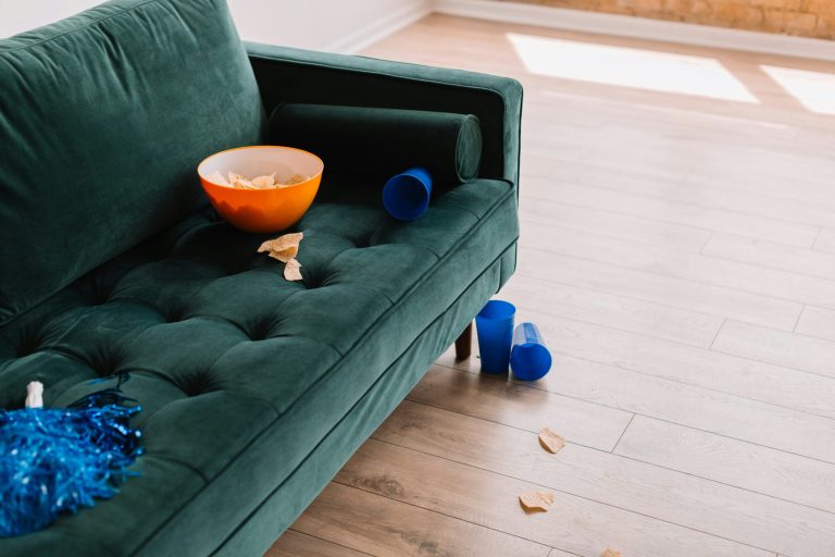 A green velvet sofa with scattered toys on a hardwood floor