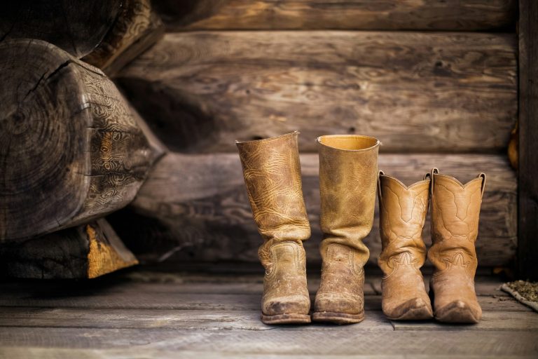 Cowboy boots lined up on a rustic wooden porch
