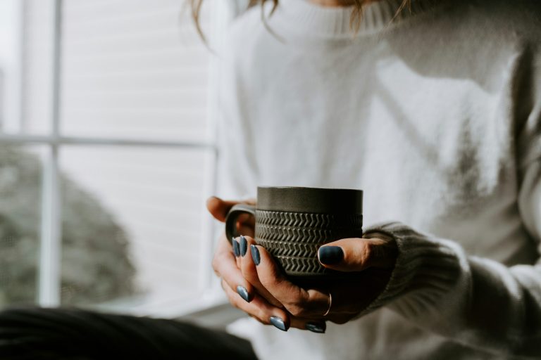 A person in a cozy sweater holding a warm mug of coffee