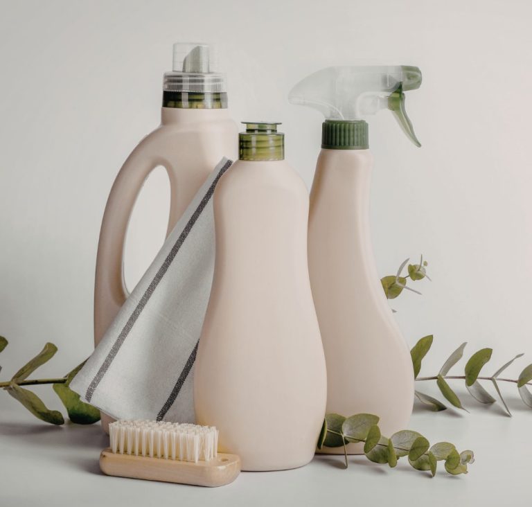 Eco-friendly cleaning bottles with a scrub brush and green leaves